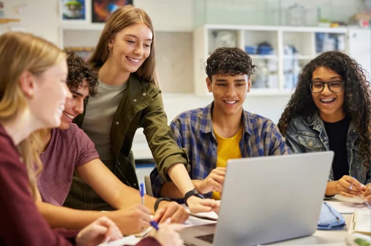 Students gathered around a laptop, working on a project together