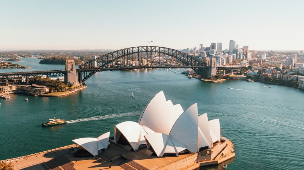 Sydney Harbour with the Opera House, Harbour Bridge, and city skyline at golden hour